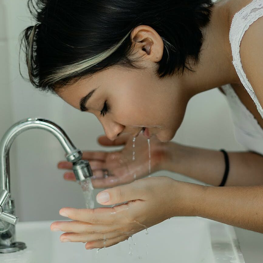 woman washing her face with water