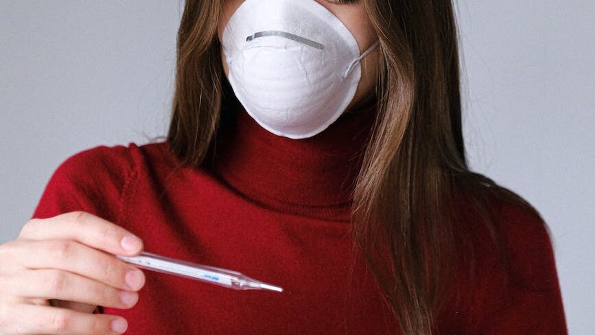 woman in face mask checking thermometer